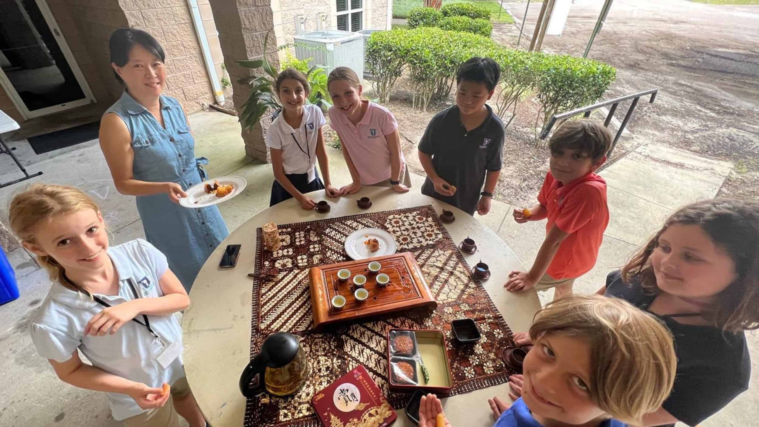 A group of USL students and a teacher surrounding a table of Chinese food and tea