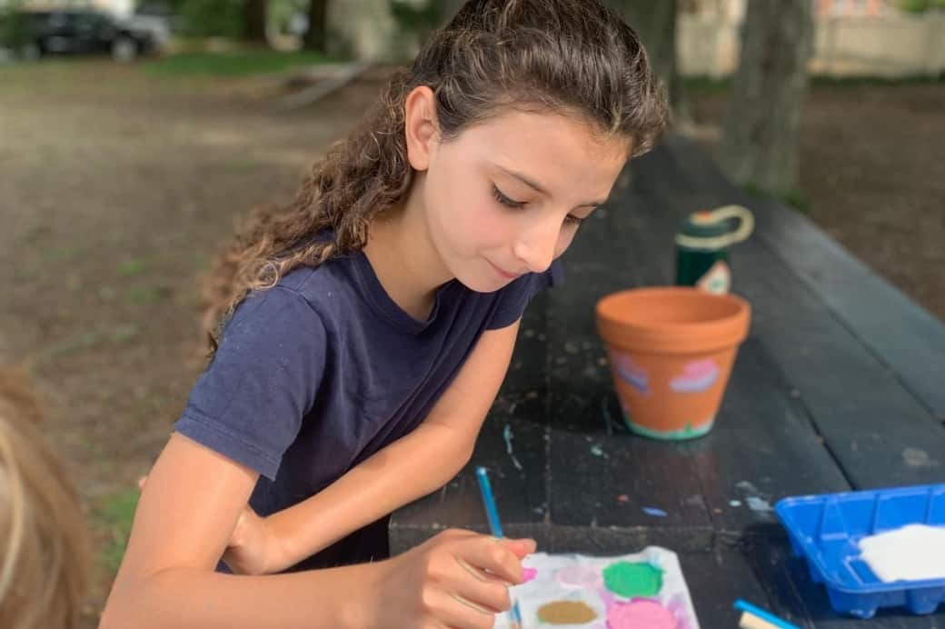 A student thoughtfully mixes paint colors to use on a flower pot